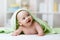 Portrait of adorable smiling baby in hooded towel lying on bed after having bathtime