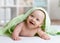 Portrait of adorable smiling baby in hooded towel lying on bed after having bathtime