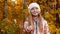 Portrait of adorable smiling girl in white hat standing in autumn park