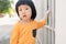 Portrait of adorable young Asian toddler smiling and looks toward the camera with curious eyes, holding house fence while morning