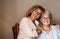 Portrait of adult beautiful daughter hugging her mother smiling, spending time together at home