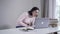 Portrait of adult Caucasian woman opening laptop and looking at screen with surprised face. Young brunette lady spying