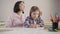 Portrait of adult caucasian woman sitting with daughter at the table. Parent helping schoolgirl with homework. Studying