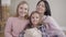 Portrait of adult Caucasian woman, teenage girl and little cute child looking at camera and smiling. Happy friendly