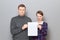 Portrait of adult couple holding together white blank paper sheet