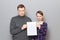 Portrait of adult couple holding together white blank paper sheet