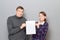 Portrait of adult couple holding together white blank paper sheet