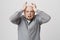 Portrait of adult male with hysterical expression holding his hands on head over white background. Bearded man terrified