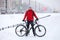 Portrait of an adult man with mountain bicycle standing on snowy bike lane on urban street, winter season with snowfall