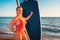 Portrait of an adult plump woman in a red swimsuit holding a sup board. The concept of active recreation at sea and