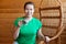 Portrait of an adult woman wearing green t-shirt holding a cup of coffee, one person sitting rattan chair at home