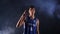 Portrait of an African American basketball player in a dark smoky studio under the spotlights. The guy hits himself in