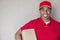 Portrait of a African American delivery man holding package against wall