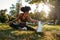 Portrait of an african american female athlete stretching her legs sitting on lawn in the park - young black woman