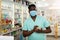 Portrait of an african american male pharmacist in a protective mask, makes important notes
