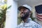 Portrait of african american male soldier standing in front of american flag outside home