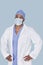 Portrait of an African American male surgeon with hands on hips over light blue background