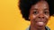 Portrait african american woman happy smiling and looking camera. Close up. Pretty curly girl isolated on yellow studio