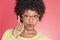 Portrait of an African American woman in retro glasses pointing upward over colored background