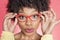 Portrait of an African American woman wearing retro style glasses over colored background