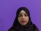 portrait of african muslim woman wearing hijab and traditional muslim clothes posing in front of purple background