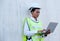 Portrait of African technician worker woman lean on cargo container wall and also hold laptop for working