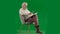 Portrait of aged bearded man on chroma key green screen background. Full shot of senior man sitting on chair reading