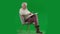 Portrait of aged bearded man on chroma key green screen. Full shot senior man sitting on chair reading book with