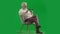 Portrait of aged bearded man on chroma key green screen. Full shot senior man sitting on chair typing bank card number