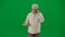 Portrait of aged bearded man on chroma key green screen. Senior man walking and looking at the camera, talks on