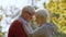 Portrait of aged Caucasian couple hugging in the park touching foreheads standing in the center of the shot senior