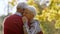 Portrait of aged Caucasian married couple tightly hugging in the park woman closing her eyes elderly people support