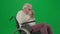 Portrait of aged disabled man on chroma key green screen. Close up senior man sitting in wheelchair feeling cold