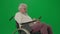 Portrait of aged disabled man on chroma key green screen. Close up senior man sitting in wheelchair surfing web on