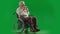 Portrait of aged disabled man on chroma key green screen. Full shot senior man in wheelchair takes photos on old film