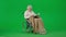 Portrait of aged disabled man on chroma key green screen. Senior man in wheelchair covered in plaid reading book