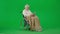 Portrait of aged disabled man on chroma key green screen. Senior man in wheelchair covered in plaid using tablet