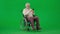 Portrait of aged man on chroma key green screen. Senior man in wheelchair typing bank card number in smartphone, buying