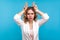 Portrait of aggressive bully woman making bull horns gesture over her head and frowning face. blue background