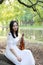 Portrait of Aisan Chinese girl woman play violin in nature park garden under a tree enjoy leisure time performance outdoor in park