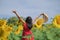 Portrait Alone Woman with Red Dress and holding hat Standing in Sun Flowers Park