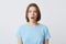 Portrait of amazed beautiful young woman in blue t shirt standing with opened mouth and feels shocked isolated over white