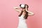 Portrait of amazed bride woman in white wedding dress, headset of virtual reality clinging to head isolated on pastel