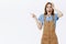 Portrait of amazed impressed good-looking caucasian female in brown overalls holding hand on head and pointing left