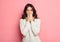 Portrait of amazed young woman over pink background