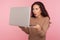 Portrait of amazed young woman standing with mouth open in surprise and reading shocking information on laptop