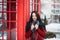 Portrait amazing smiled winter young woman walking on street full with snow Red telephone box, british style