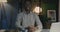 Portrait of ambitious African American entrepreneur sitting at desk in dark office smiling looking at camera