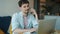 Portrait of ambitious young man working with laptop and talking on mobile phone in apartment