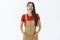 Portrait of amused carefree and optimistic young attractive asian girl with dark hair in brown overalls holding hands in